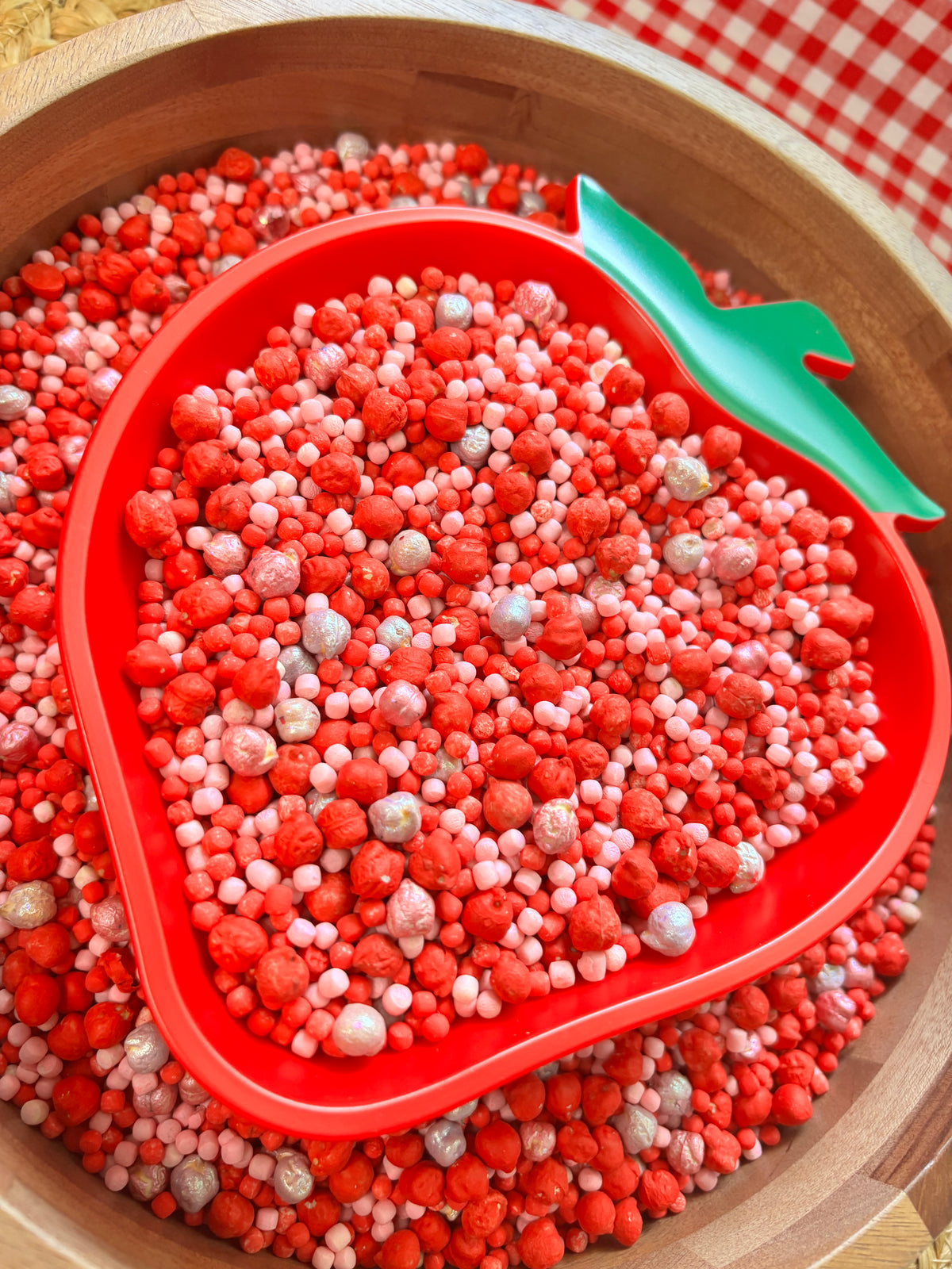 Close-up of strawberry sensory filler with colorful manipulatives for sensory play.